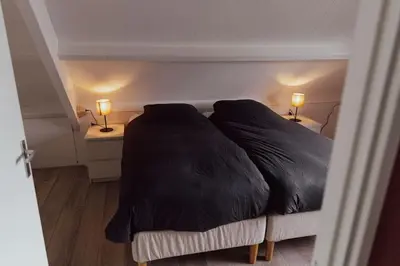 a bedroom with a large bed with two lamps on tables at Cosy bungalow with private garden in Noordwijkerhout