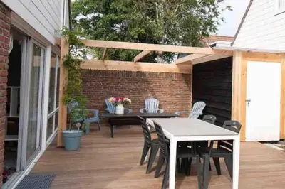 a patio with a table and chairs on a deck at Cosy bungalow with private garden in Noordwijkerhout