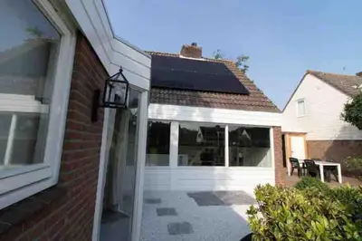 a house with a garage door with a solarium at Cosy bungalow with private garden in Noordwijkerhout