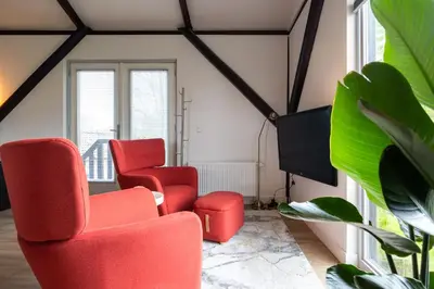 a living room with red chairs and a tv at Studio Hooischuur Alkmaar/Bergen in Alkmaar