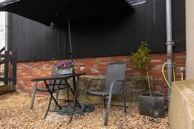 two chairs and a table and an umbrella at Studio Hooischuur Alkmaar/Bergen in Alkmaar