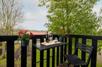 a table and chairs on a black fence with flowers at Studio Hooischuur Alkmaar/Bergen in Alkmaar