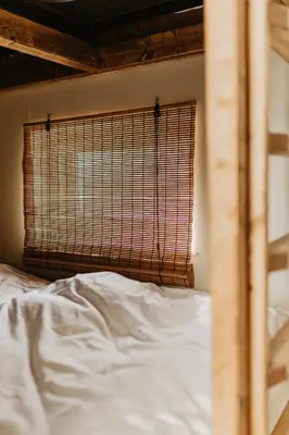 a bedroom with a bed and a window with white sheets at Strandhuisjes Zoomers aan Zee in Castricum