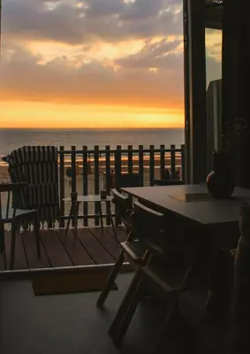 a table and chairs on a balcony with a view of the ocean at Strandhuisjes Zoomers aan Zee in Castricum