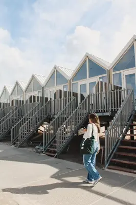 a woman walking past a row of metal buildings at Strandhuisjes Zoomers aan Zee in Castricum