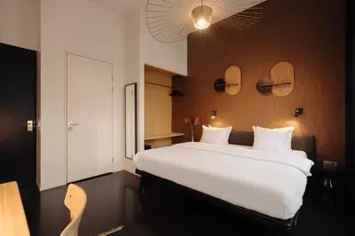a bedroom with a large bed with white sheets at Hotel V Frederiksplein in Amsterdam