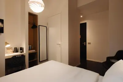 a bedroom with a white bed and a mirror at Hotel V Frederiksplein in Amsterdam