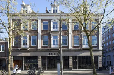 a large building on a city street with trees at Hotel V Frederiksplein in Amsterdam
