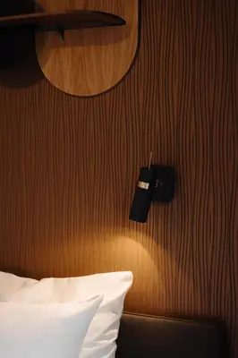 a bedroom with a wooden wall with a bed and a lamp at Hotel V Frederiksplein in Amsterdam