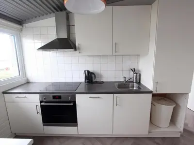 a white kitchen with a sink and a stove at Beachhouse II in Bergen aan Zee