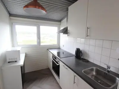 a kitchen with white cabinets and a sink and a window at Beachhouse II in Bergen aan Zee