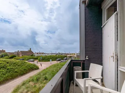 a balcony with two chairs and a street at Beachhouse II in Bergen aan Zee
