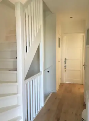 a hallway with a white staircase and a white door at just like home in Haarlem