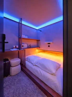 a bedroom with a large bed with a blue lighting at The Hyve Capsule hostel Amsterdam in Amsterdam
