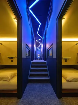 a hallway with two beds and a blue light at The Hyve Capsule hostel Amsterdam in Amsterdam