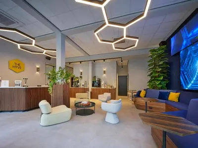 a lobby with a blue couch and white chairs at The Hyve Capsule hostel Amsterdam in Amsterdam