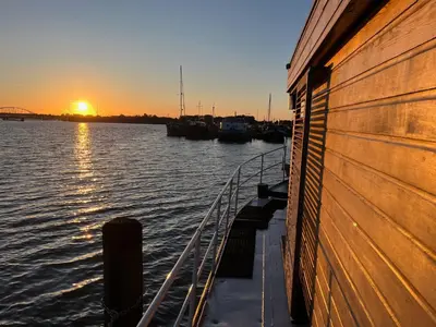 a boat is docked on the water at sunset at Casey's Lake View House Boat in Amsterdam