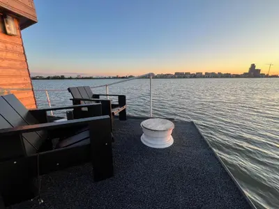 a dock with chairs and a bench on the water at Casey's Lake View House Boat in Amsterdam
