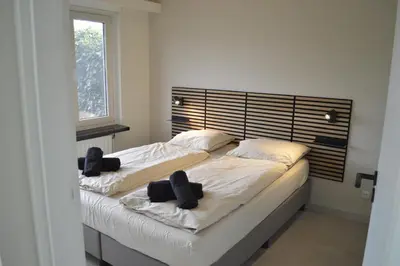 a bedroom with two beds with black headboards at Cozy bungalow (Near beach, tulip fields, etc) in Noordwijkerhout