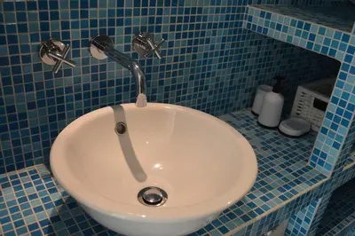 a white sink in a blue tiled bathroom at Cozy bungalow (Near beach, tulip fields, etc) in Noordwijkerhout