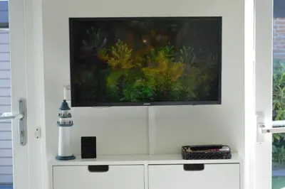 a flat screen tv sitting on top of a white cabinet at Cozy bungalow (Near beach, tulip fields, etc) in Noordwijkerhout
