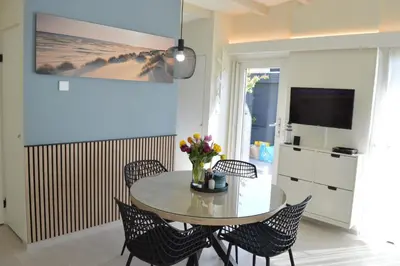 a dining room with a table and chairs and a television at Cozy bungalow (Near beach, tulip fields, etc) in Noordwijkerhout