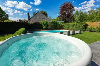 a hot tub in a backyard with a pool at Rode Tiny House met zwembad in Zeewolde