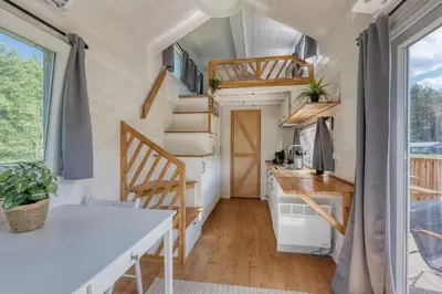 a tiny house with a kitchen and stairs at Rode Tiny House met zwembad in Zeewolde