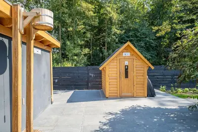 a small wooden shed with a door in a yard at Rode Tiny House met zwembad in Zeewolde