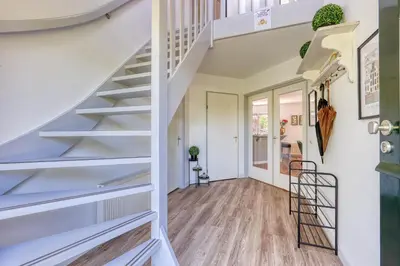 a staircase in a home with white walls and wood floors at Forest Villa with shared pool & Eco Wellness in Zeewolde