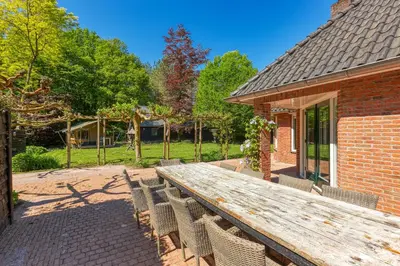a wooden table and chairs on a patio at Forest Villa with shared pool & Eco Wellness in Zeewolde