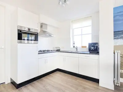 a white kitchen with white cabinets and a window at Holiday Home Tapuit 6-1 by Interhome in Noordwijk