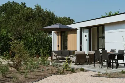 a patio with a table and chairs and an umbrella at MarinaPark Residentie Bloemendaal in Vogelenzang