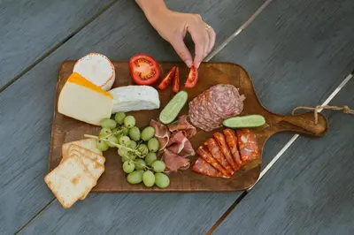 a wooden cutting board with meat cheese and vegetables at MarinaPark Residentie Bloemendaal in Vogelenzang