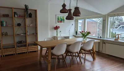 a dining room with a wooden table and chairs at Kust Geluk in Schoorl
