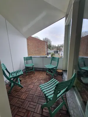 a patio with green chairs on a balcony at Kust Geluk in Schoorl