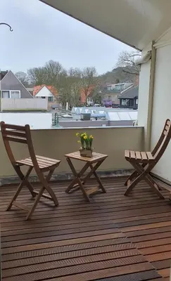 two chairs and a table on a porch with a window at Kust Geluk in Schoorl
