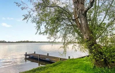 a tree sitting next to a dock on a lake at Stunning Stacaravan In Reeuwijk in Reeuwijk
