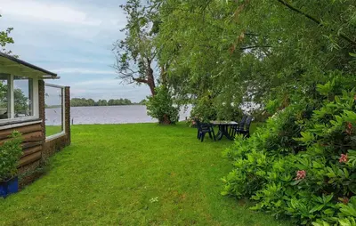 a yard with a table and chairs next to a lake at Stunning Stacaravan In Reeuwijk in Reeuwijk