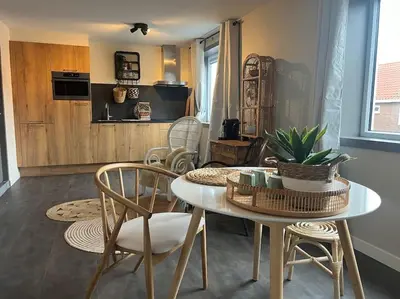 a living room with a table and chairs and a kitchen at Mint aan het strand in Egmond aan Zee