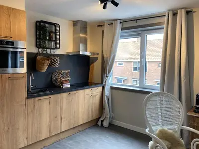 a kitchen with a window and a counter with a chair at Mint aan het strand in Egmond aan Zee