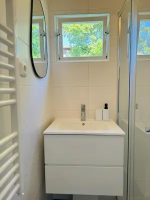 a white bathroom with a sink and a mirror at Familie Vakantiehuis - Zonneweelde in Noordwijk aan Zee