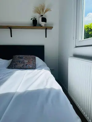 a bedroom with a bed with a pillow and a window at Familie Vakantiehuis - Zonneweelde in Noordwijk aan Zee