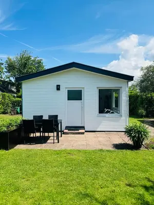 a small white shed with a table and chairs at Familie Vakantiehuis - Zonneweelde in Noordwijk aan Zee