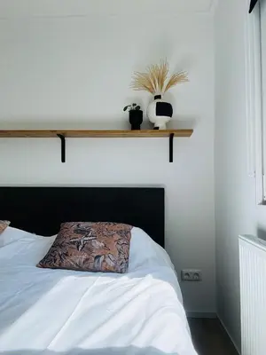 a bedroom with a bed with a wooden shelf on the wall at Familie Vakantiehuis - Zonneweelde in Noordwijk aan Zee