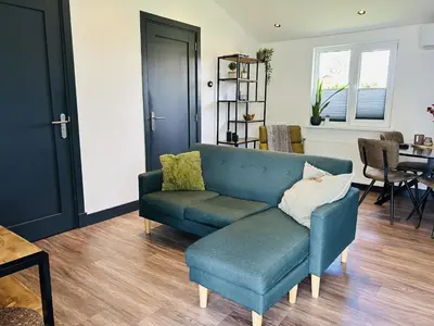 a living room with a blue couch and a table at Bungalowpark de Horn - 821 in Dirkshorn