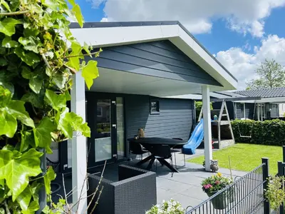 a house with a patio with a table and a slide at Bungalowpark de Horn - 821 in Dirkshorn
