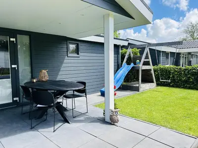 a patio with a table and a playground at Bungalowpark de Horn - 821 in Dirkshorn