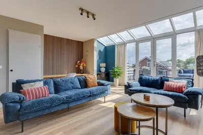 a living room with blue couches and a table at Meerzicht 57 - 3 bedroom appt with sunny terrace in Uitgeest