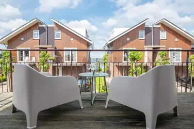 two chairs and a table on a balcony with buildings at Meerzicht 57 - 3 bedroom appt with sunny terrace in Uitgeest